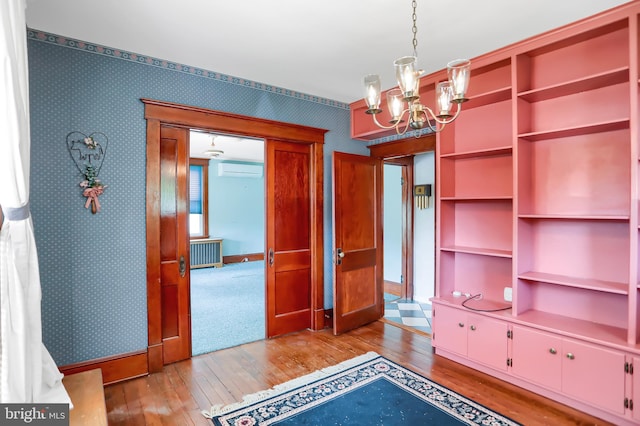 interior space featuring an AC wall unit, a chandelier, and hardwood / wood-style floors