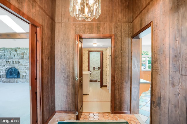 corridor with light tile patterned floors, an inviting chandelier, and wooden walls