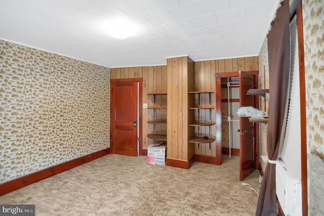 unfurnished bedroom featuring light colored carpet and wood walls