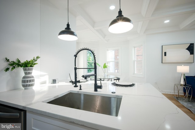 kitchen with light stone counters, hanging light fixtures, sink, coffered ceiling, and hardwood / wood-style flooring