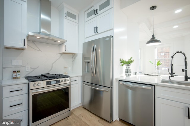 kitchen featuring sink, wall chimney exhaust hood, stainless steel appliances, and white cabinetry