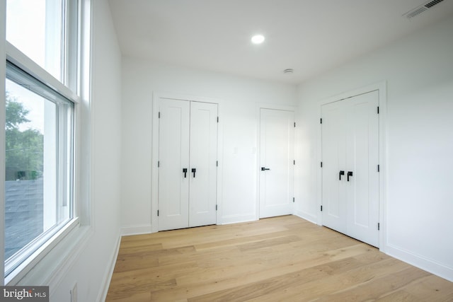 unfurnished bedroom featuring light wood-type flooring and two closets