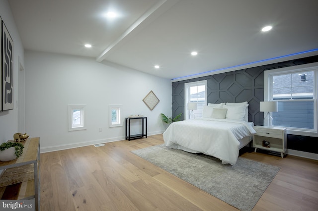 bedroom featuring multiple windows, light hardwood / wood-style floors, and lofted ceiling