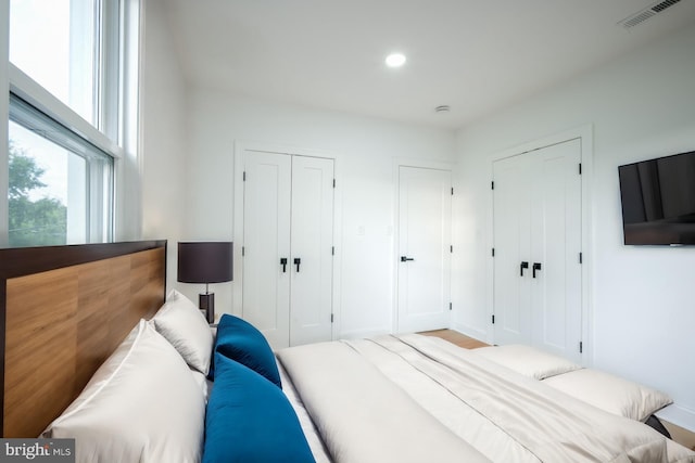 bedroom with light hardwood / wood-style floors and multiple closets