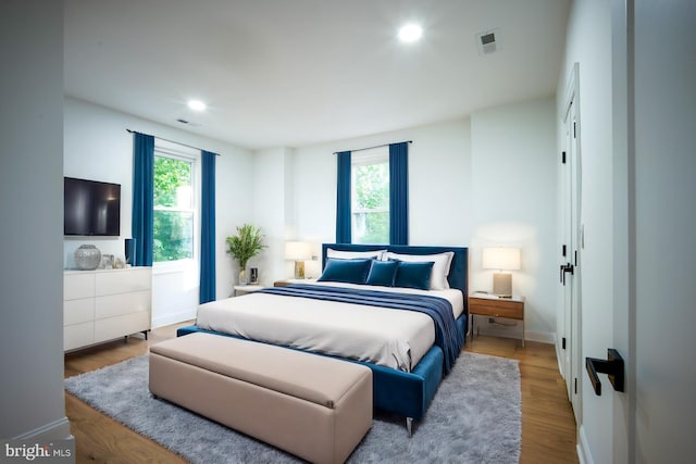 bedroom with multiple windows and light wood-type flooring