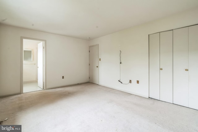 unfurnished bedroom with light colored carpet and connected bathroom