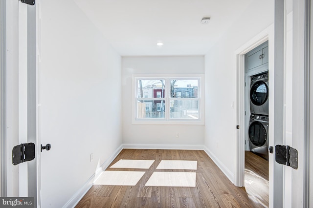 laundry area with light wood-type flooring and stacked washer / drying machine