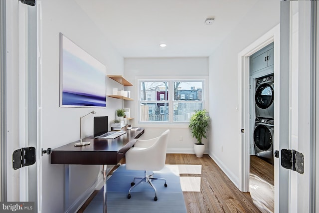 office space featuring stacked washing maching and dryer and light hardwood / wood-style flooring