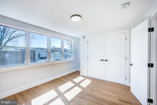 unfurnished bedroom with light wood-type flooring and a closet