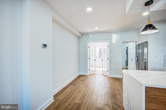 kitchen featuring wood-type flooring, pendant lighting, and light stone counters