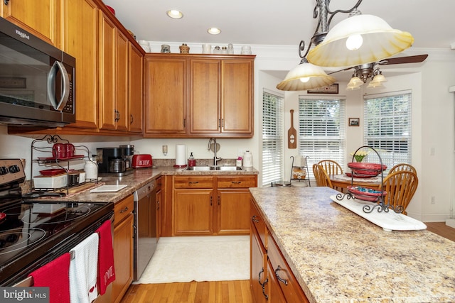 kitchen featuring sink, decorative light fixtures, stainless steel appliances, crown molding, and light hardwood / wood-style floors