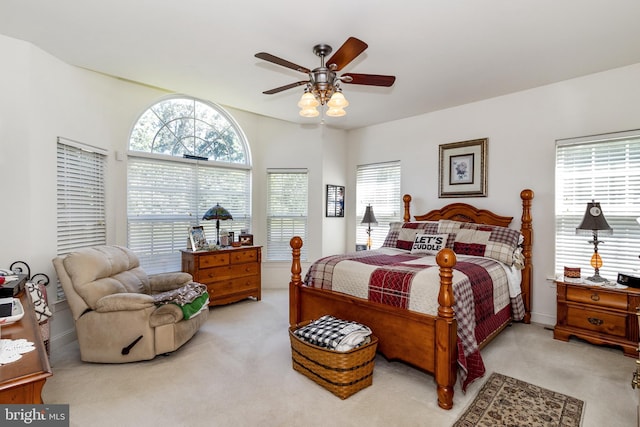 carpeted bedroom featuring multiple windows and ceiling fan