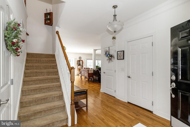 foyer entrance featuring ornamental molding, light hardwood / wood-style flooring, and ornate columns