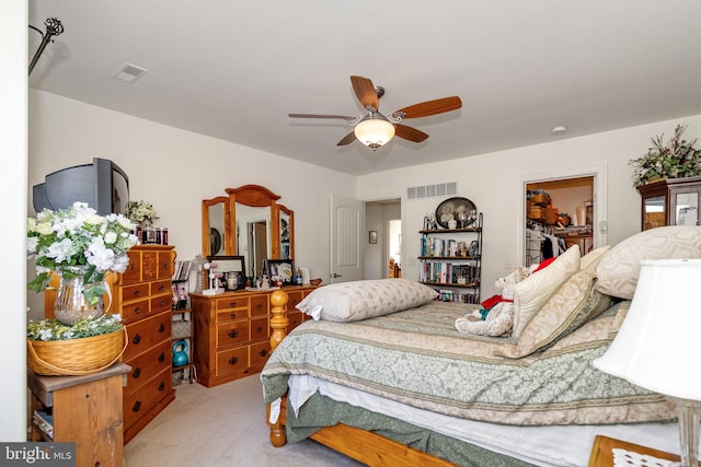 bedroom with ceiling fan, a closet, light carpet, and a walk in closet