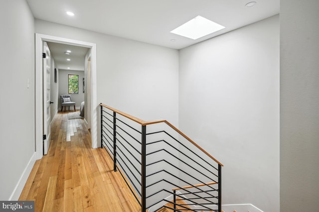 hallway with a skylight and light hardwood / wood-style floors