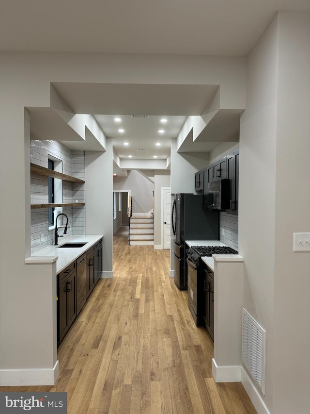 kitchen with decorative backsplash, light hardwood / wood-style flooring, dark brown cabinetry, and sink