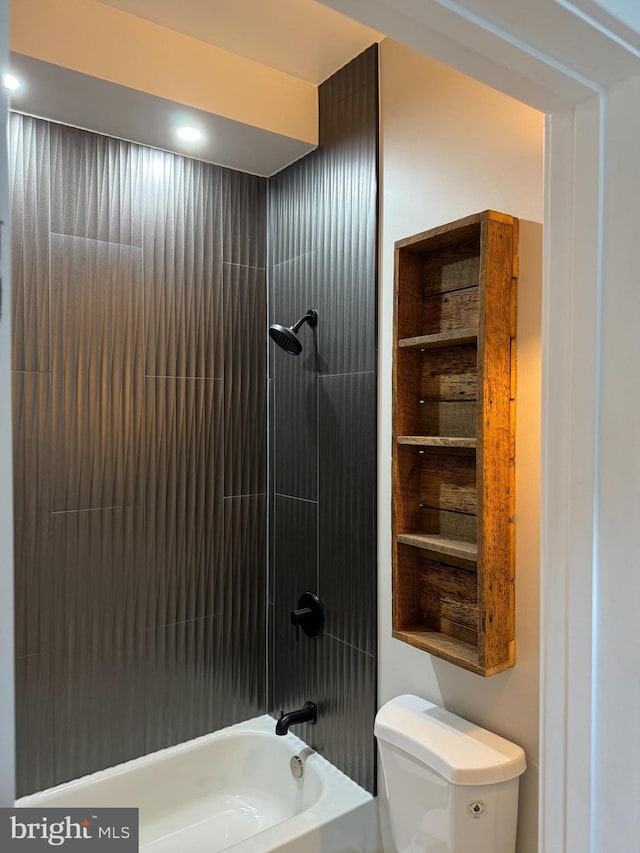 bathroom with tiled shower / bath combo and toilet