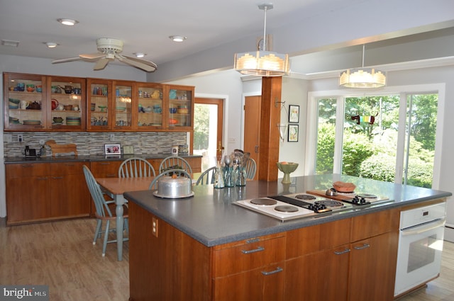 kitchen with a healthy amount of sunlight, ceiling fan with notable chandelier, light hardwood / wood-style flooring, and tasteful backsplash