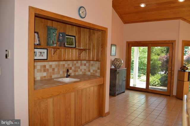 kitchen with light tile patterned flooring, wood ceiling, lofted ceiling, sink, and backsplash