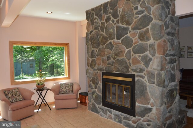 living room with a fireplace, beam ceiling, and light tile patterned floors