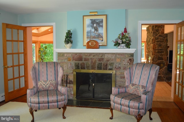 living area with a healthy amount of sunlight, a fireplace, and hardwood / wood-style flooring