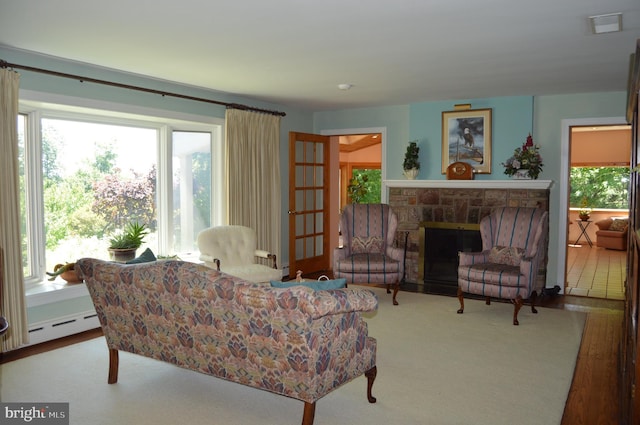 living room featuring carpet floors, baseboard heating, plenty of natural light, and a fireplace