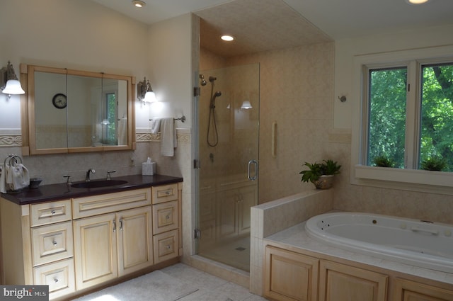 bathroom featuring shower with separate bathtub, tile patterned flooring, vanity, and tile walls