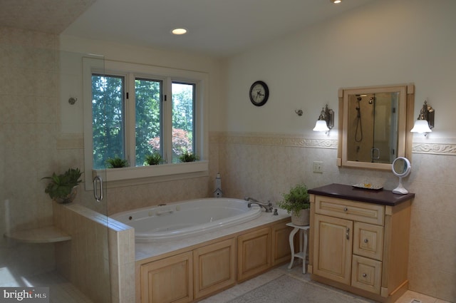 bathroom with tile walls, tile patterned floors, independent shower and bath, and vanity