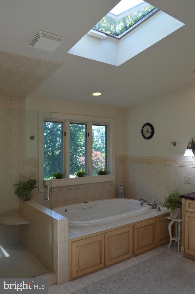 bathroom with independent shower and bath, a skylight, tile walls, and tile patterned flooring