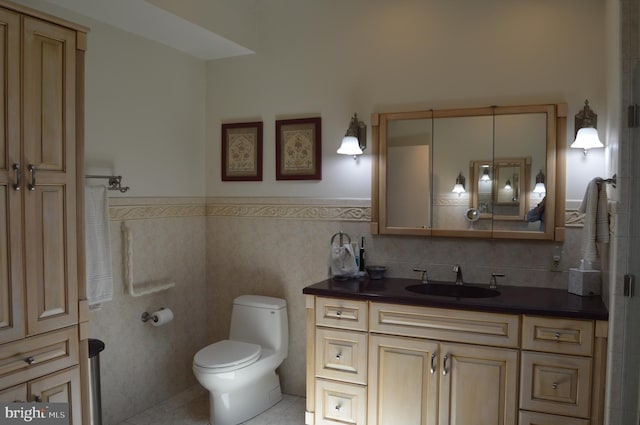 bathroom with tile walls, vanity, toilet, and tile patterned floors