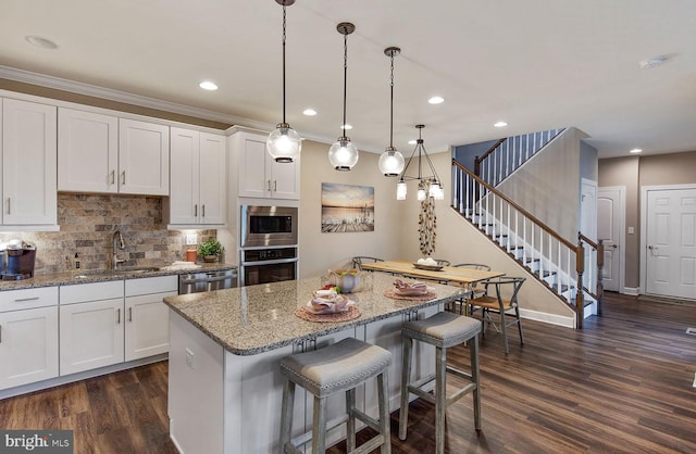 kitchen featuring sink, a kitchen island, dark wood-type flooring, white cabinetry, and appliances with stainless steel finishes