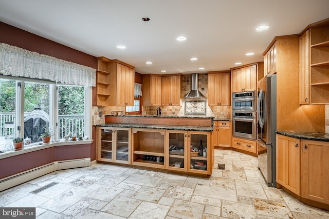 kitchen featuring sink, wall chimney range hood, stainless steel appliances, backsplash, and dark stone countertops