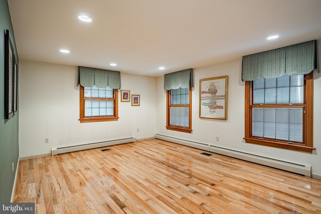 spare room featuring baseboard heating and light hardwood / wood-style flooring