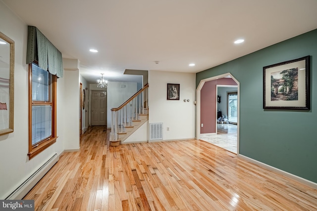 empty room with a baseboard radiator, a chandelier, and light hardwood / wood-style floors