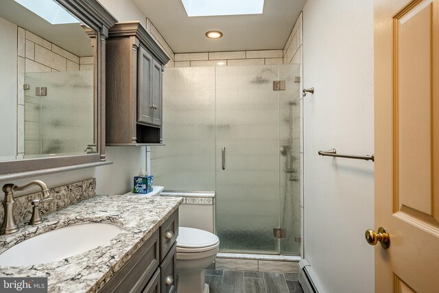 bathroom featuring vanity, toilet, a skylight, and an enclosed shower