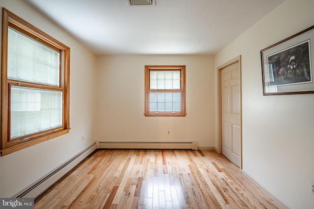 interior space featuring multiple windows, light wood-type flooring, and a baseboard radiator