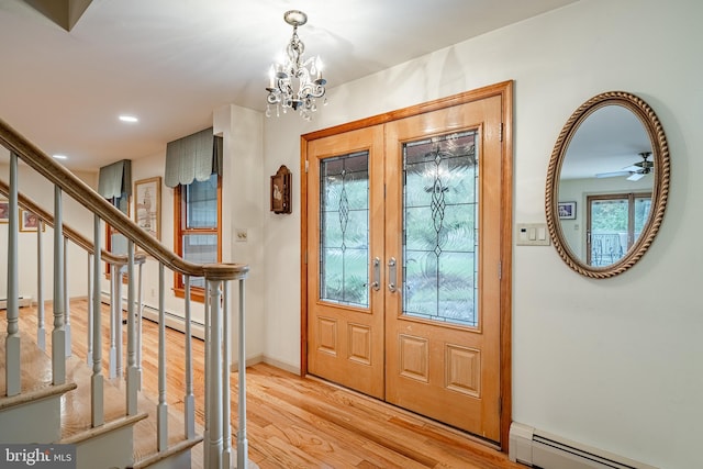 foyer featuring french doors, ceiling fan with notable chandelier, light hardwood / wood-style flooring, and a baseboard heating unit