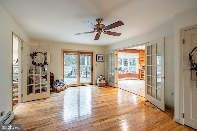 entryway with a healthy amount of sunlight, light hardwood / wood-style floors, baseboard heating, and french doors