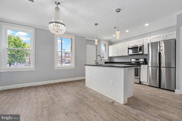 kitchen featuring appliances with stainless steel finishes, light wood-type flooring, hanging light fixtures, and white cabinets