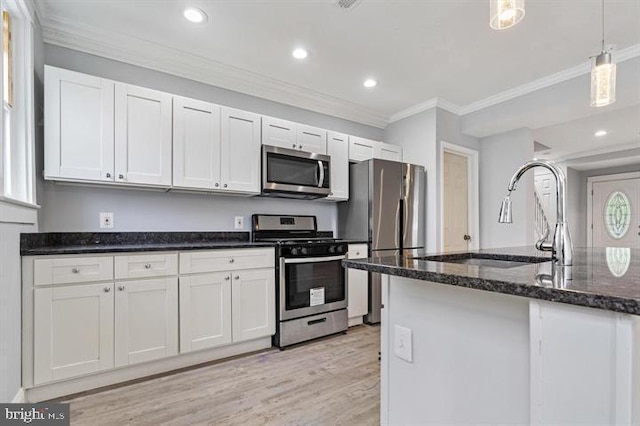 kitchen featuring pendant lighting, sink, white cabinetry, stainless steel appliances, and light hardwood / wood-style floors