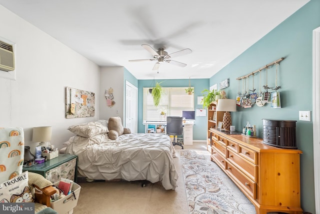 bedroom featuring a wall mounted AC, light carpet, and ceiling fan