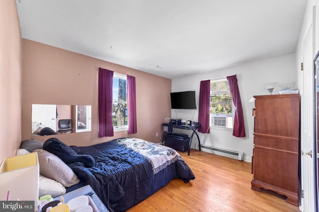 bedroom with cooling unit, baseboard heating, and light hardwood / wood-style floors