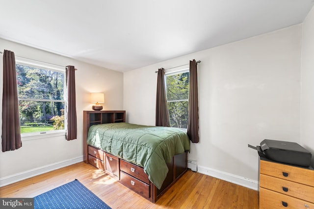 bedroom with light wood-type flooring and baseboard heating