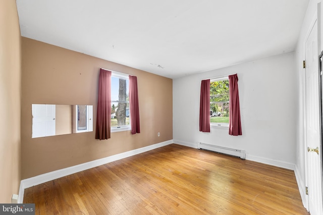 unfurnished room featuring a baseboard radiator and light wood-type flooring