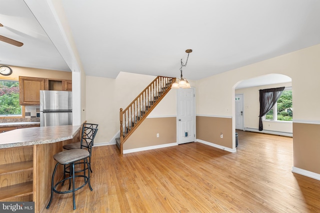 dining area featuring ceiling fan, a baseboard radiator, and light wood-type flooring