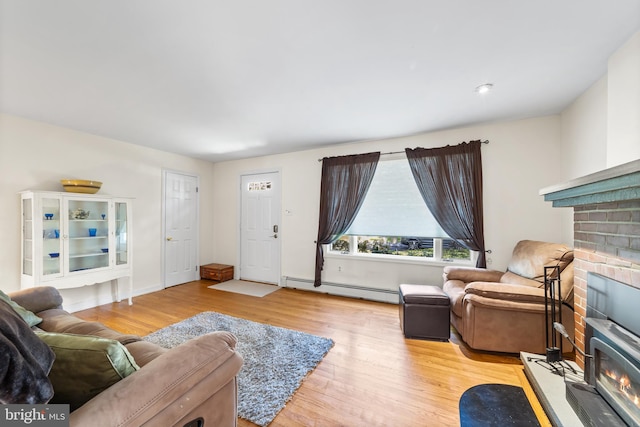 living room with a fireplace, a baseboard heating unit, and light hardwood / wood-style flooring