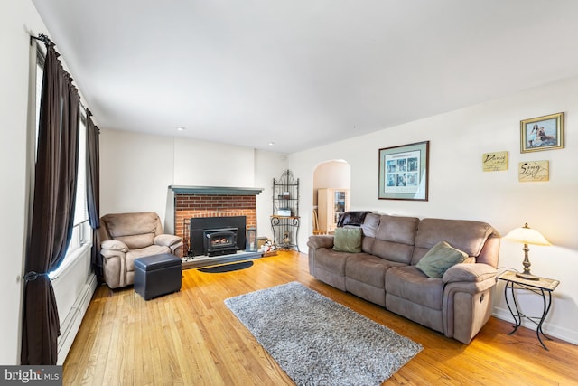 living room with hardwood / wood-style flooring, a baseboard heating unit, and a brick fireplace