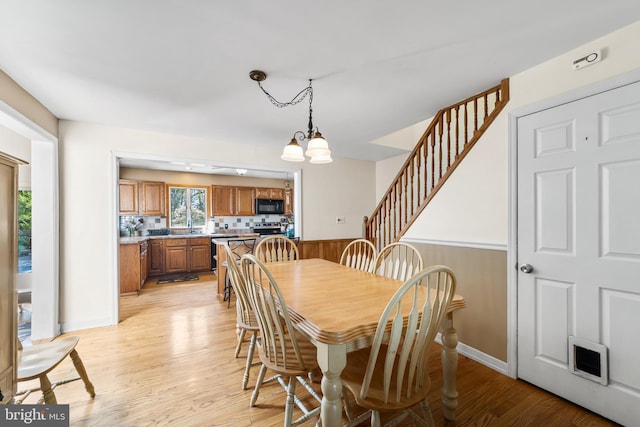 dining room with an inviting chandelier, sink, and light hardwood / wood-style floors