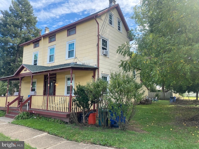 view of front of home with a chimney, a front lawn, fence, and a porch