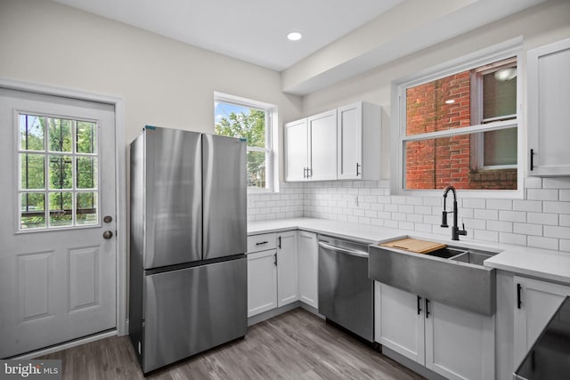 kitchen featuring appliances with stainless steel finishes, decorative backsplash, white cabinetry, and light hardwood / wood-style flooring